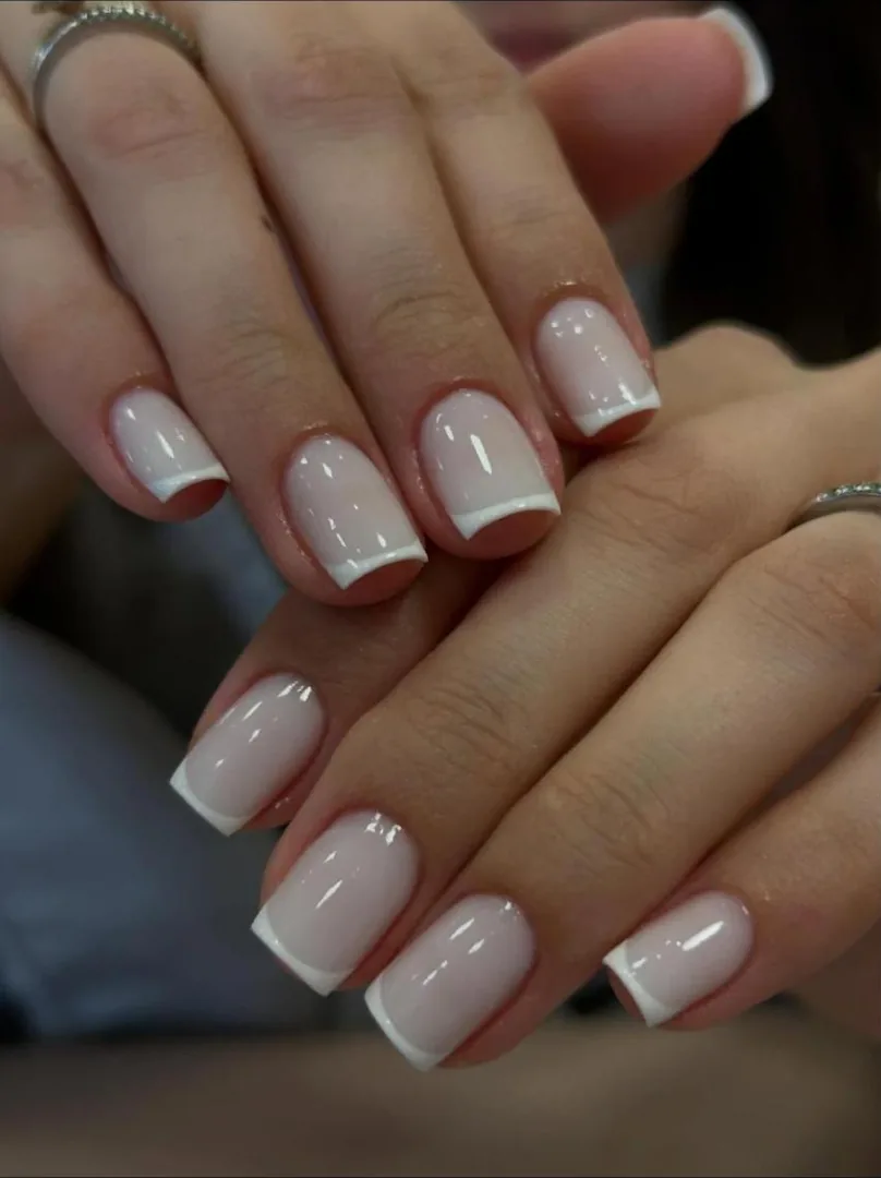 Mãos com unhas curtas em francesinha branca